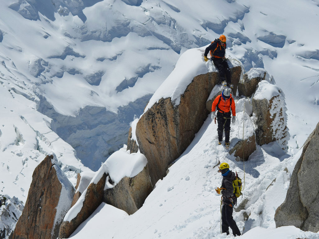 Three climbers descending from a snowy mountain